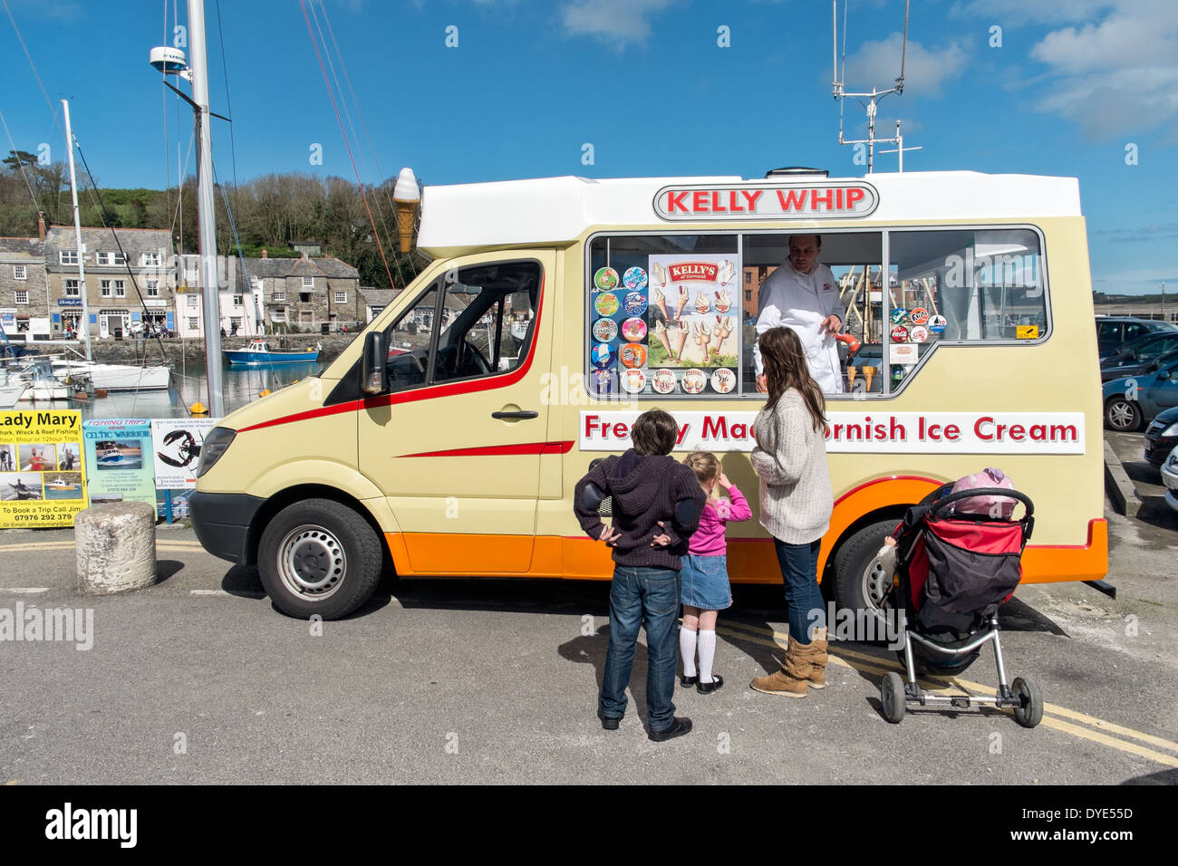 Eine Mutter mit kleinen Kindern, die von einem traditionellen britischen Cornish Eiswagen am sonnigen Hafen von Padstow, Cornwall, UK kaufen Stockfoto