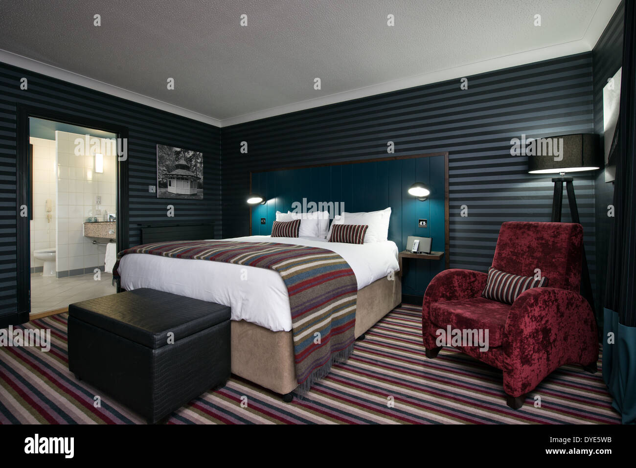 Eine komfortable, stilvolle Bett mit gestreiften Zubehör mit einem blauen Kopfteil in einer Suite im Devere Hotel, Swindon, Wiltshire Stockfoto