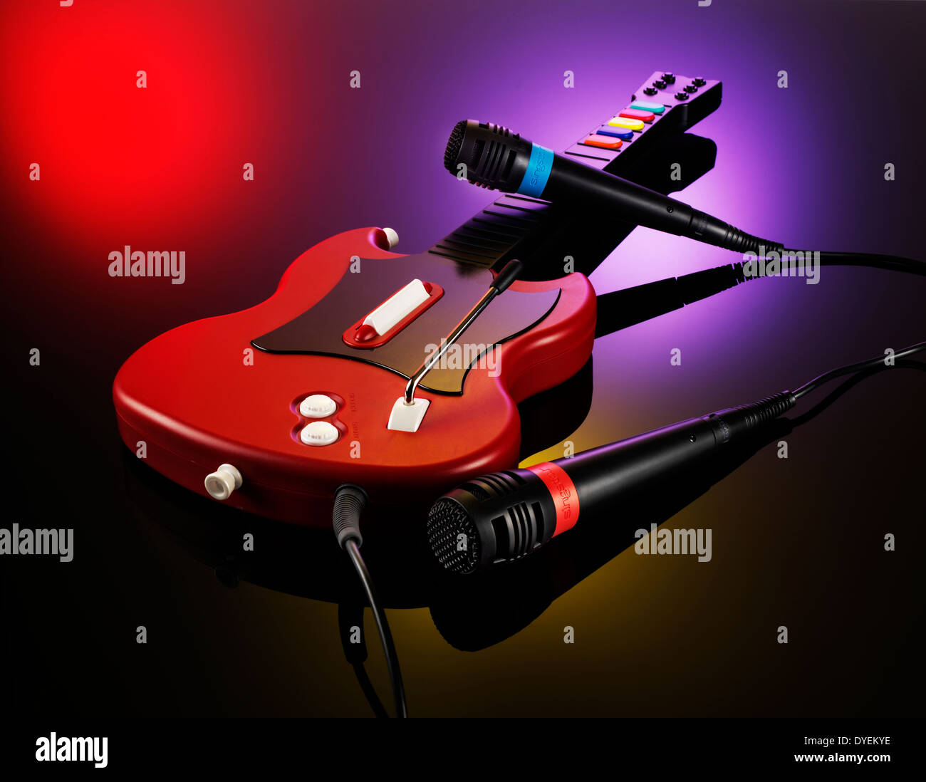 ZWEI MIKROFONE UND EINE GITARRE AUS DEM VIDEOSPIEL GUITAR HERO AUF EINEM ROSA SCHWARZ ROTEN HINTERGRUND Stockfoto