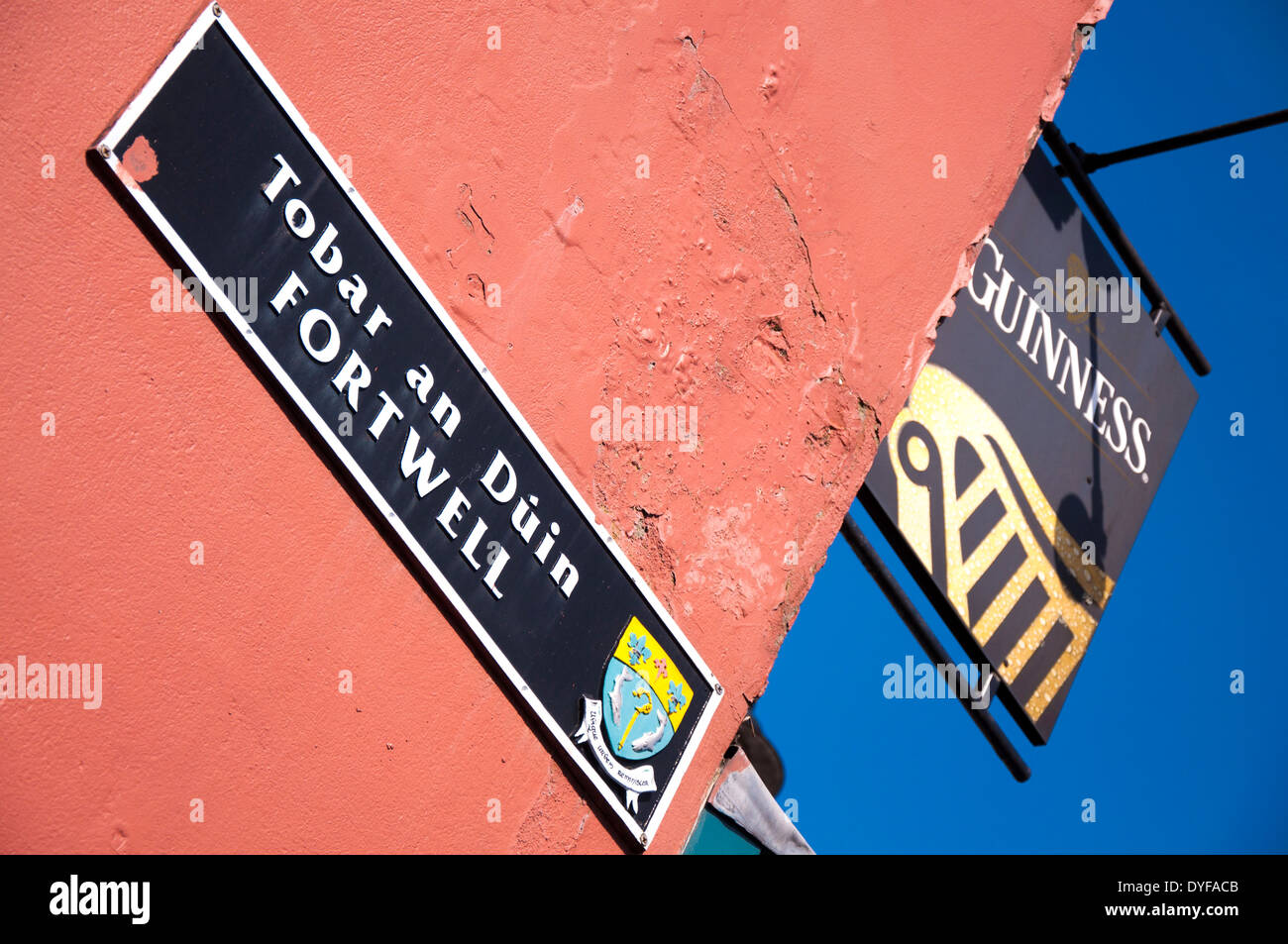 Guinness-Zeichen vor einer Bar in County Donegal Letterkenny-Irland und Straßenschild in Gälisch und englischer Sprache Stockfoto