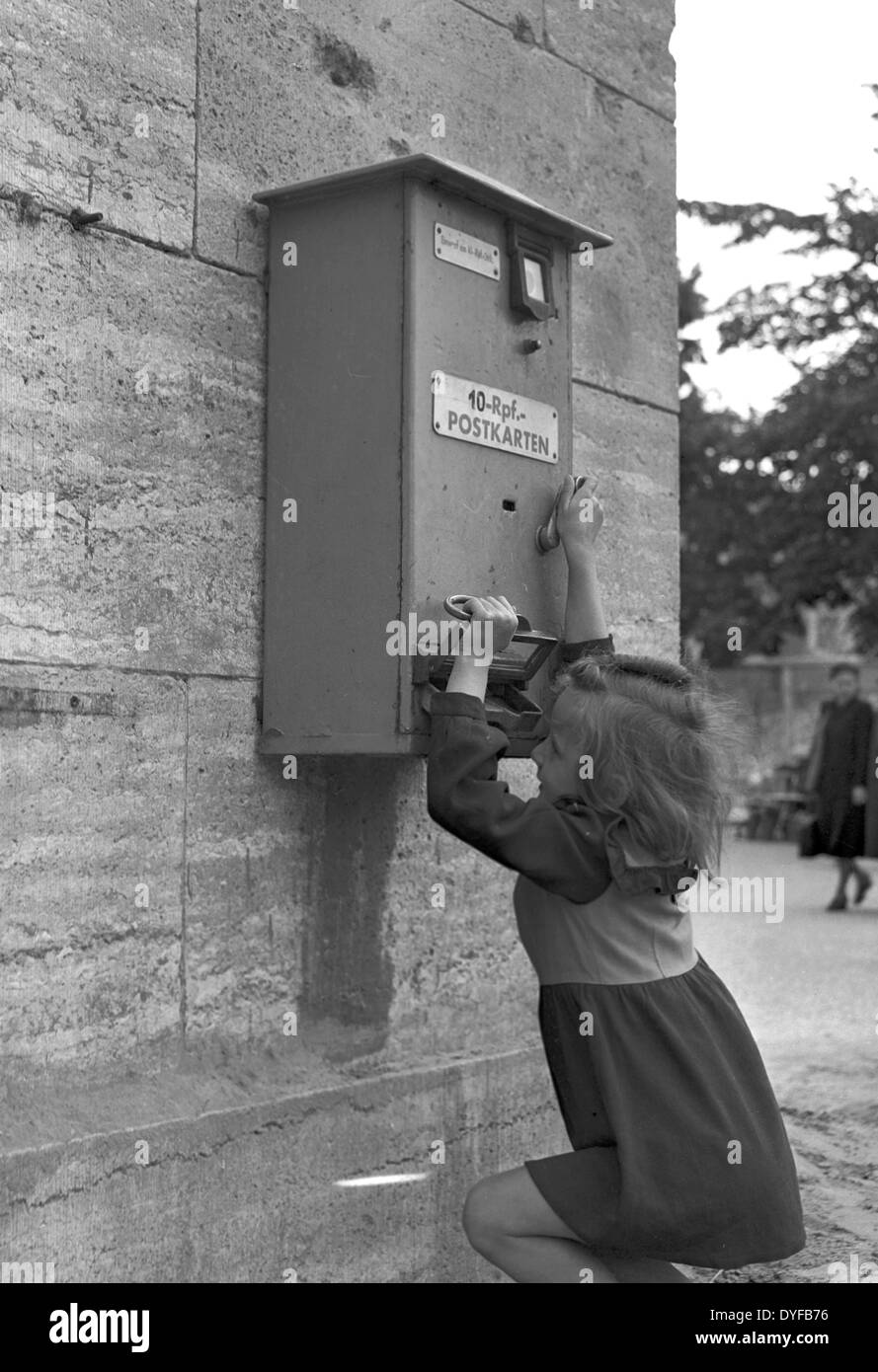 Eine Mädchen spielt mit einem Automaten für Postkarten, die für 10 Reichspfennig, Berlin, 1948 gekauft werden konnte. Bis Juni 1948 die neue Währung eingeführt wurde, war die Reichsmark in den westlichen Besatzungszonen noch gültig. Mit der Einführung der Deutschen Mark verloren die alte Währung seine Gültigkeit. Foto: Zbarchiv - blockiert für Bildübertragung Stockfoto