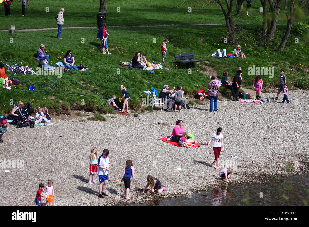 Menschen, die zum Sonnenbaden in Ilkley, West Yorkshire in der Nähe des Flusses Wharfe Stockfoto