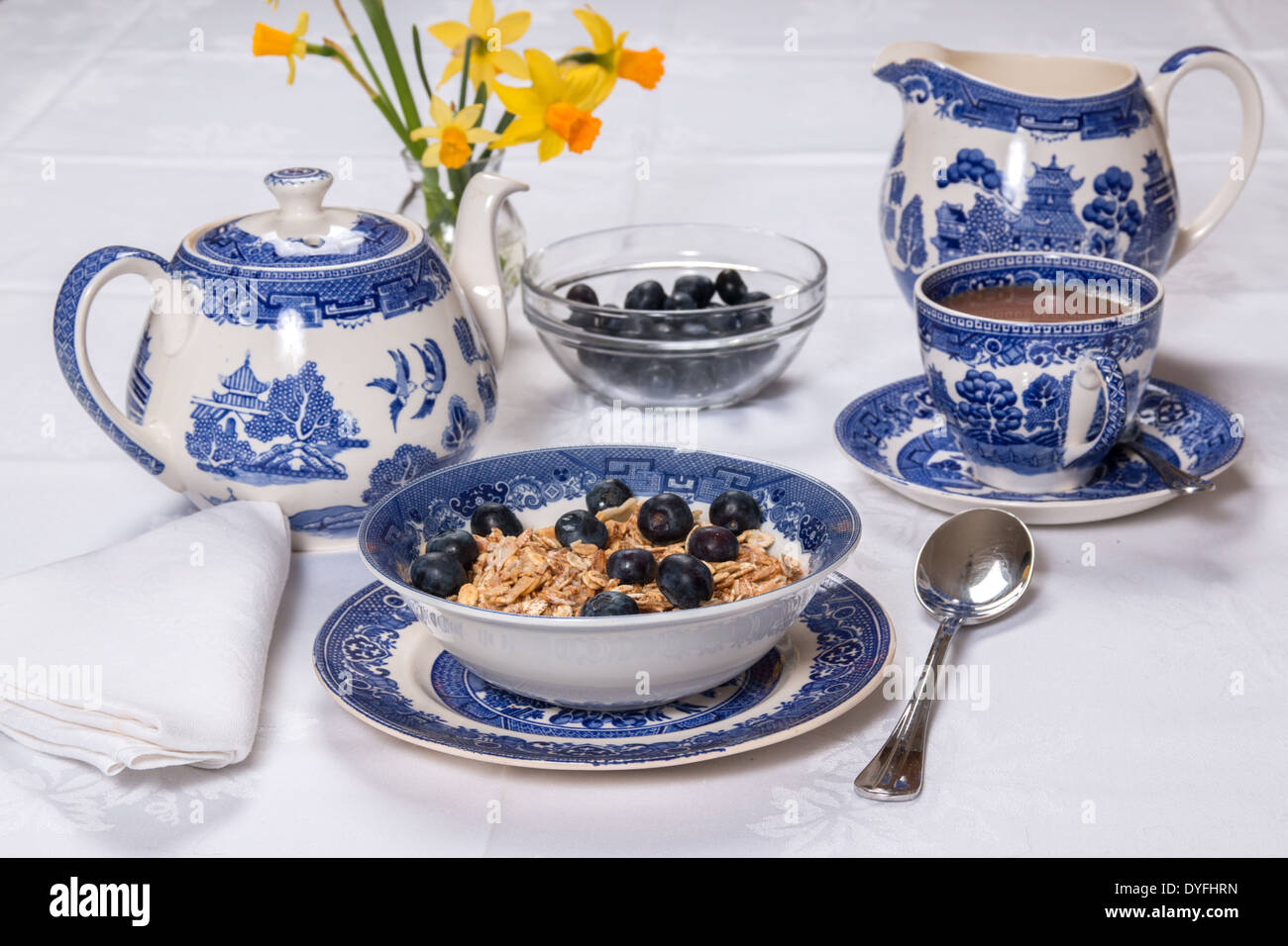 Frühstück mit Müsli/Müsli und Heidelbeeren Muster Geschirr auf einer weißen Damast Tischdecke mit Tee und Milch (21 von 26) Stockfoto