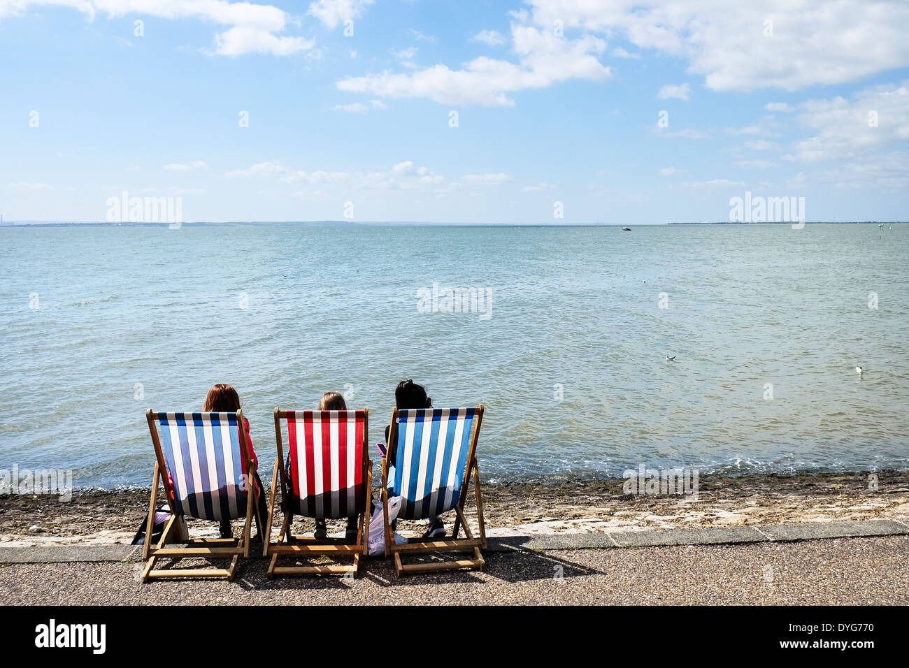 Drei Leute sitzen auf Liegestühlen an der Southend Seafront in Essex. Stockfoto