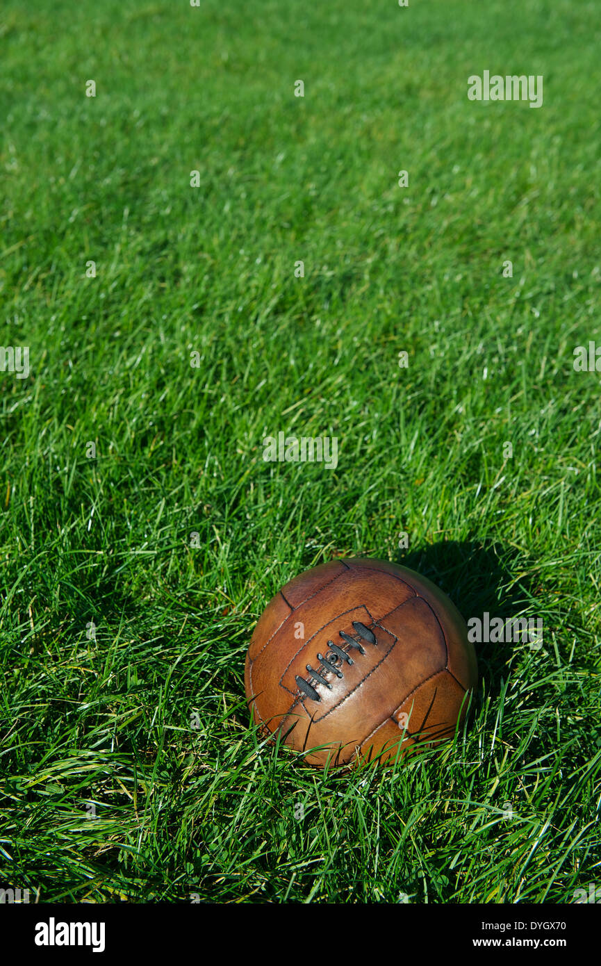 Vintage braun Fußball Fußball sitzt im hellen sonnigen grünen Wiese Stockfoto