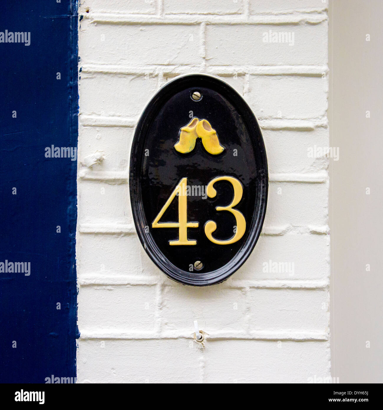 Gegossen Sie aus Metall Hausnummer 43. Schwarz lackiert und gelb auf einer  ovalen Platte mit Holzschuhen Stockfotografie - Alamy