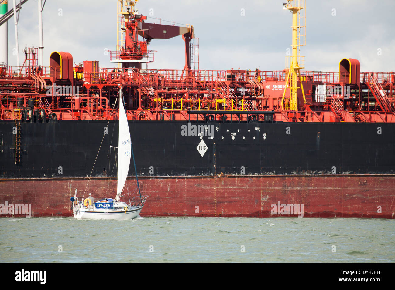 Ein Segelboot, ein Tanker in der Cleddau Mündung, Pembrokeshire Wales vorbei Stockfoto