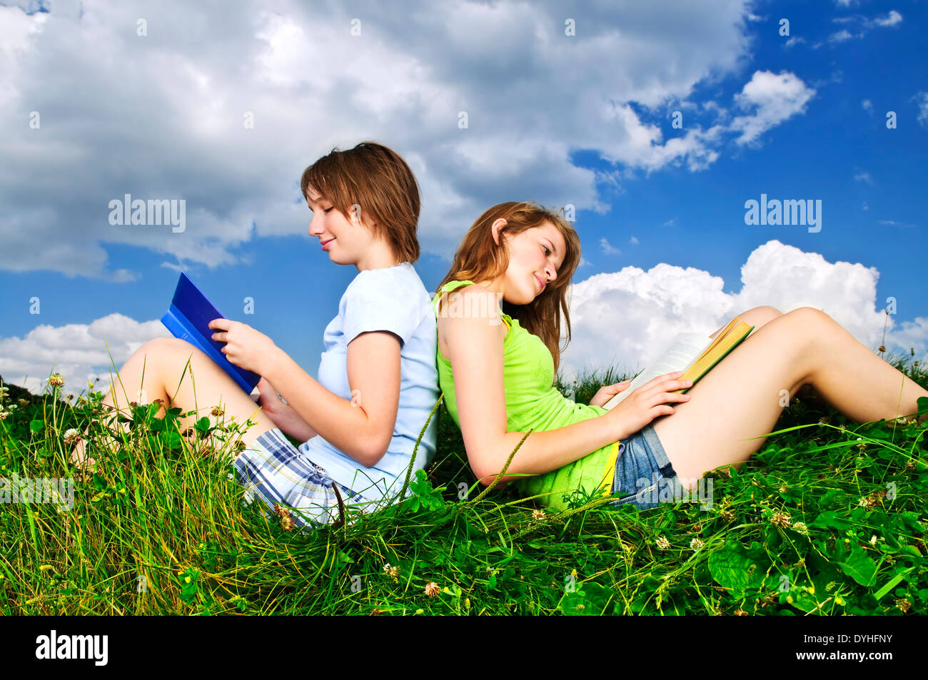 Zwei Mädchen Bücher lesen zusammen draußen auf dem Rasen im Sommer Stockfoto