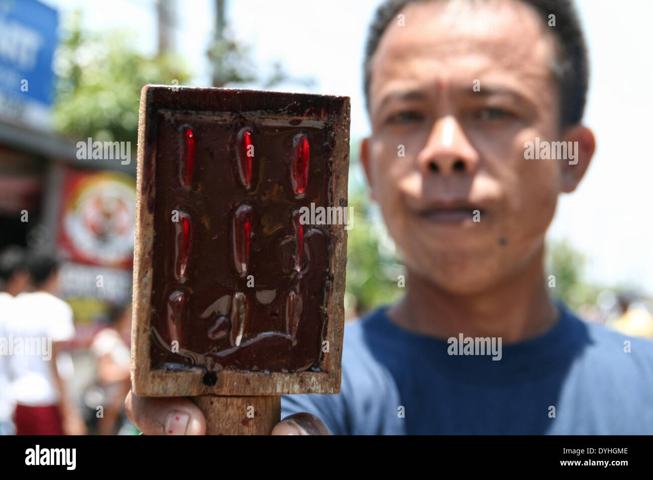 San Fernando, Philippinen. 18. April 2014.  Ein Mann mit einem Paddel wie Gerät mit scharfen Glasscherben, verwendet um die Haut zu öffnen, bevor Büßer die Rücken Peitsche konnte. Zehntausende von Einheimischen und ausländische Touristen strömten in Cutud in Pampanga Zeuge der jährlichen Karfreitag Kreuzigung Riten von reuigen Gläubigen. Büßer barfuß unter der Mittagssonne während die blutigen Rücken Auspeitschen. (Foto: J Gerard Seguia/Pacific Press/Alamy Live-Nachrichten) Stockfoto