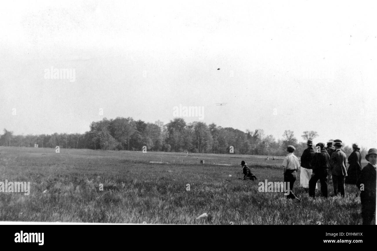 Z. B. Leonhardt besondere Sammlung Foto Gruppe von Menschen in einem Feld mit kaum sichtbaren Doppeldecker fliegen in Stockfoto