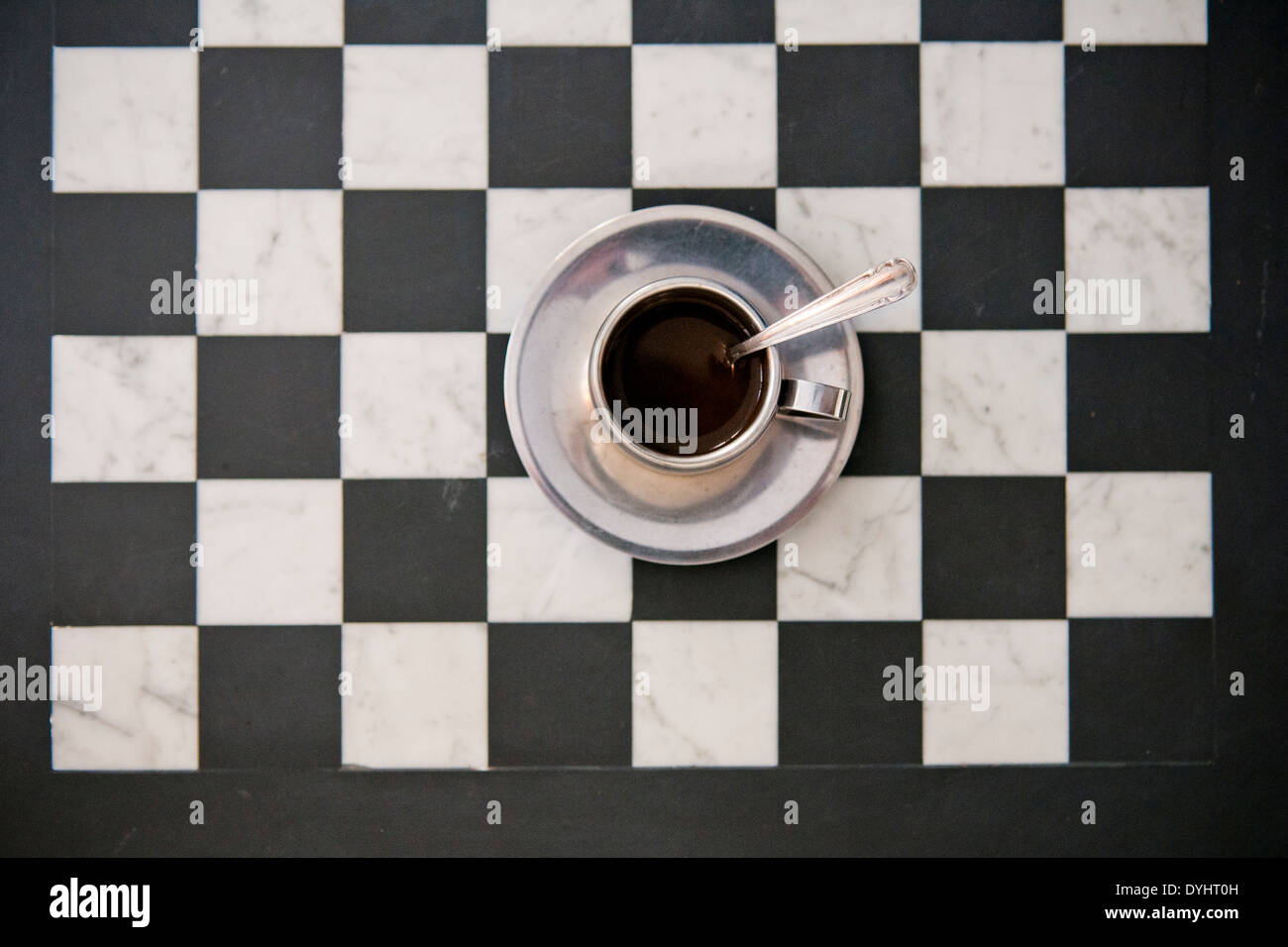 Tasse Kaffee und Untertasse auf Checker Board, High Angle View Stockfoto