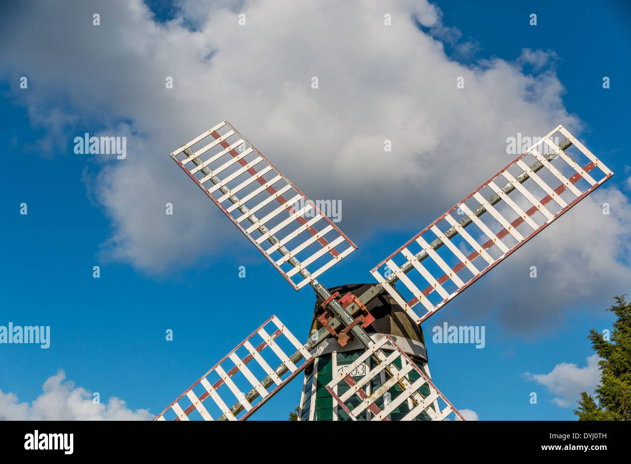 Eine holländische Windmühle gegen Wolken am blauen Himmel. Stockfoto