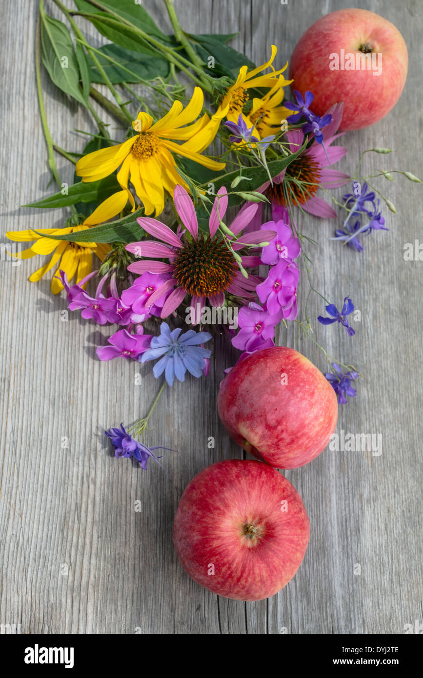 ländliche Stillleben mit Blumenstrauß und Äpfel auf Holz Hintergrund Stockfoto