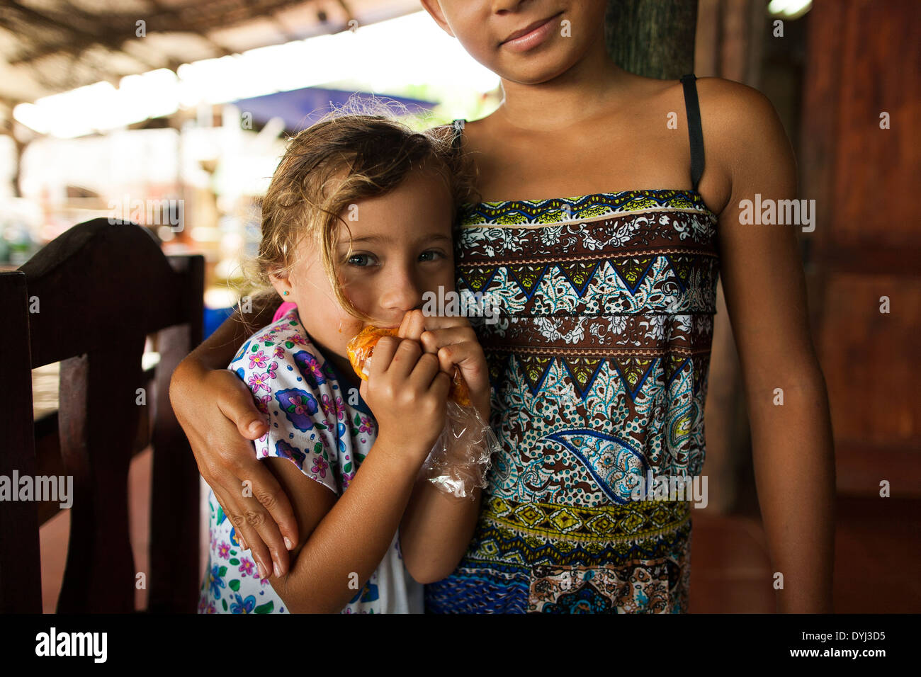 Zwei niedliche Costa Rica Schwestern halten einander in ein kleines familiengeführtes Restaurant in Golfito, Costa Rica Stockfoto
