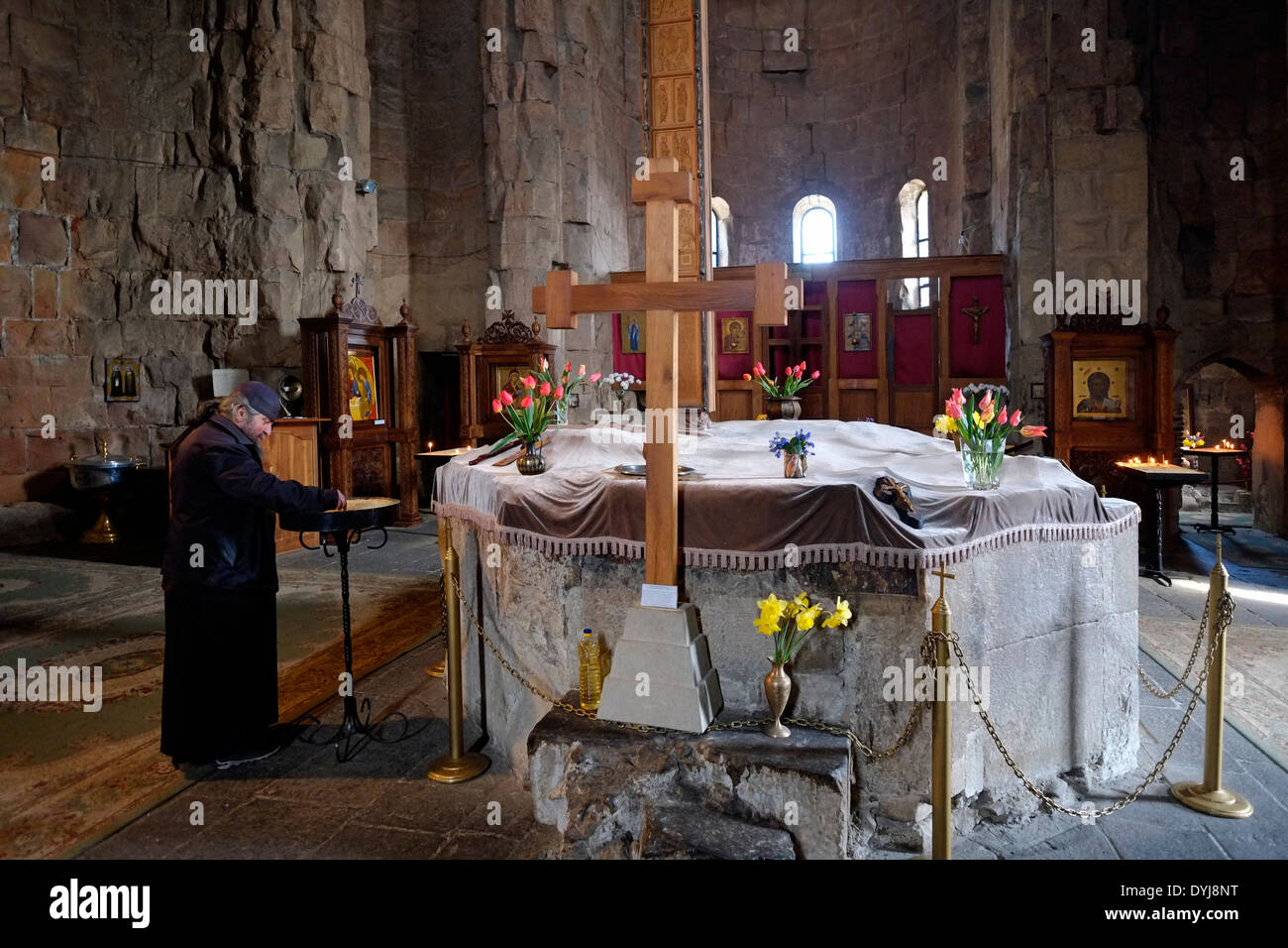 Ein georgisch-orthodoxer Priester zündet Kerzen an dem georgisch-orthodoxen Jvari-Kloster aus dem 6. Jahrhundert an, das sich auf dem felsigen Berggipfel am Zusammenfluss der Flüsse Mtkvari und Aragvi befindet, mit Blick auf die Stadt Mzcheta in der Republik Georgien Stockfoto