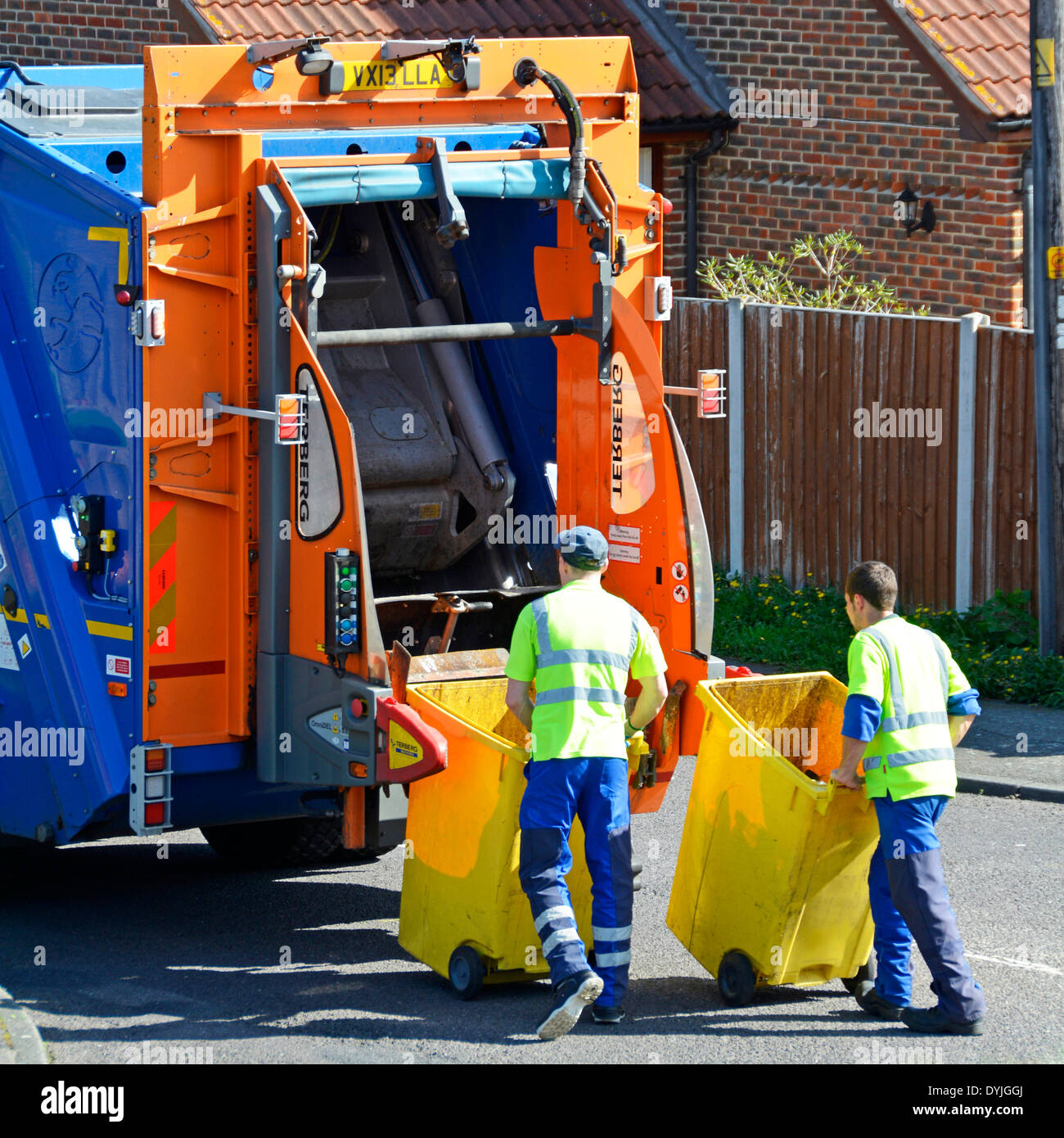 Dustmen arbeiten bei Rückseite des Rates Müllwagen Wheelie Lagerplätze auf Hebebühne zum Kippen in LKW platzieren Stockfoto