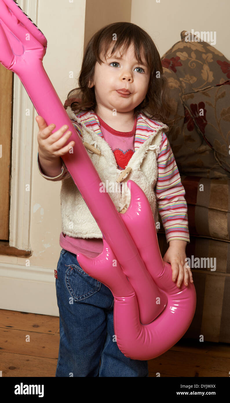 2 - Jahre altes Mädchen mit aufblasbaren Gitarre spielen Stockfoto