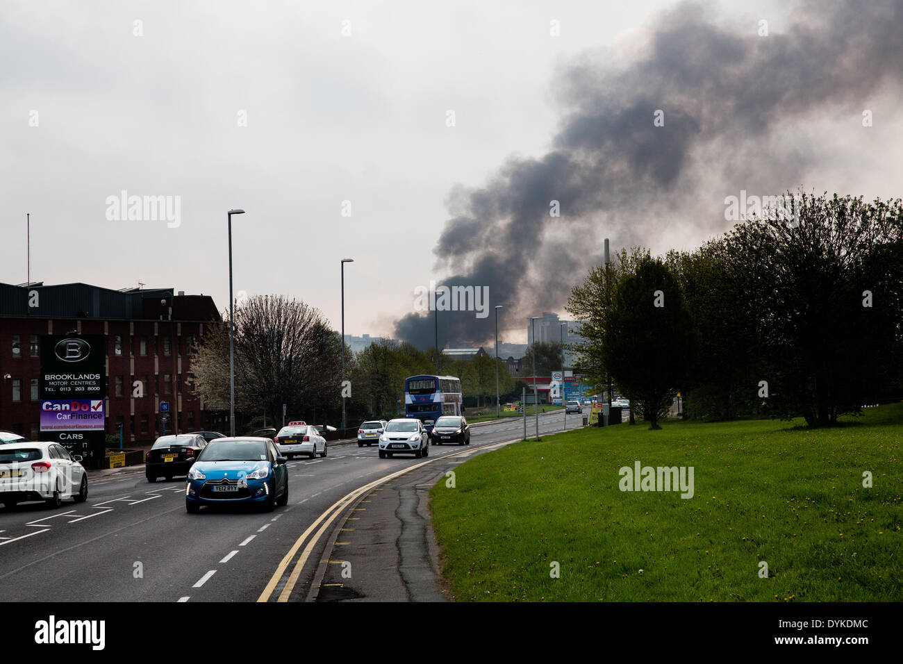 Leeds, West Yorkshire, UK, 21. April 2014. Verkehr auf der A647 Armley Straße. Ein Pall von Rauch in der Luft hängt, wie Feuerwehrleute einen Großbrand in einem Gewerbegebiet Leeds anzugehen. Das Feuer brach bei ca. 01:50 in den Räumlichkeiten des Tradpak eine Chemikalie Verpackung und recycling-Anlage im Bereich Armley der Stadt. Die Fabrik liegt in der Nähe des Stadtzentrums und Anwohner aufgefordert ihre Fenster und Türen geschlossen, weil der potenziell toxischen Chemikalien beteiligt zu halten. Bildnachweis: Ian Wray/Alamy Live-Nachrichten Stockfoto