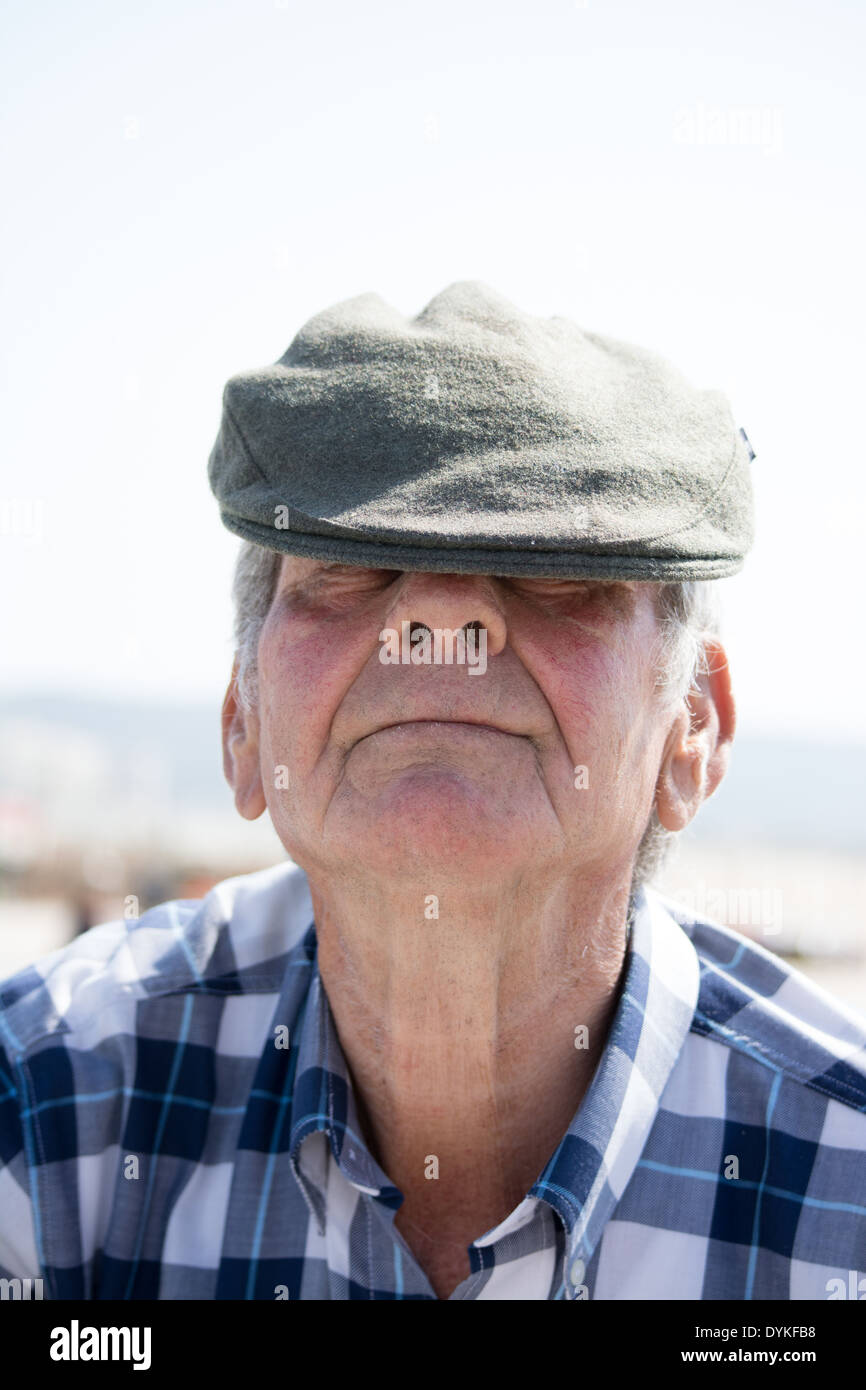 ein Alter Mann versteckt sich hinter einer Motorhaube Stockfoto