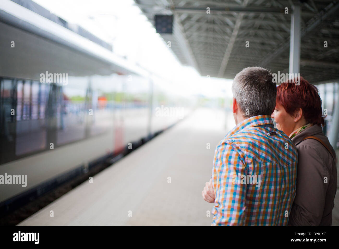 Eltern stehen auf der Plattform in einem Bahnhof winken verabschieden, als der Zug mit ihrem Kind die Station verlässt. Stockfoto