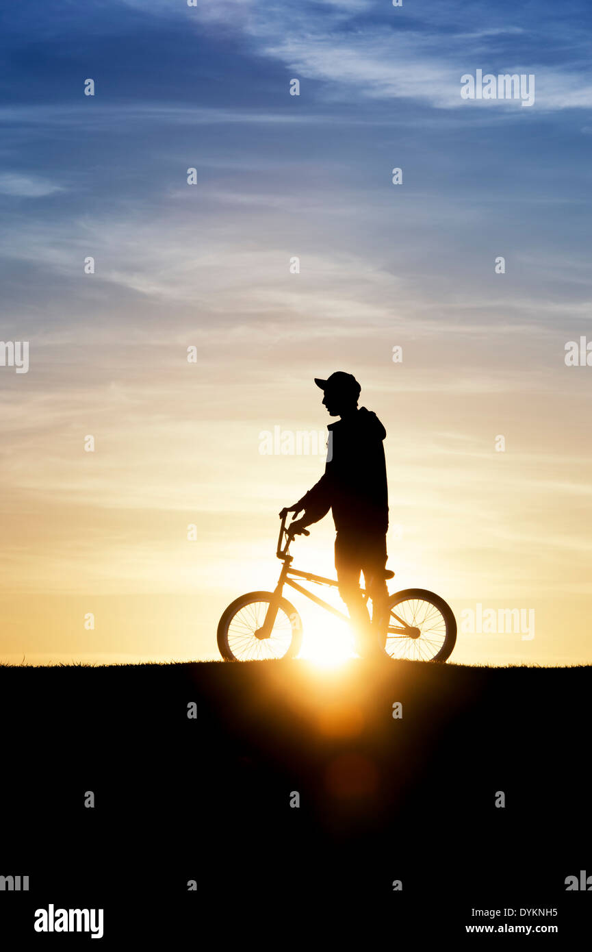 Junge Mann mit seinem BMX-Fahrrad mit Sonne Objektiv flare. Silhouette Stockfoto