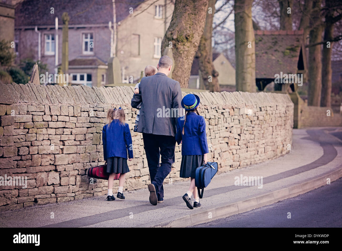 Eine elegant gekleidete Vater, Hand in Hand mit seinen Kindern und zu Fuß zur Schule Stockfoto