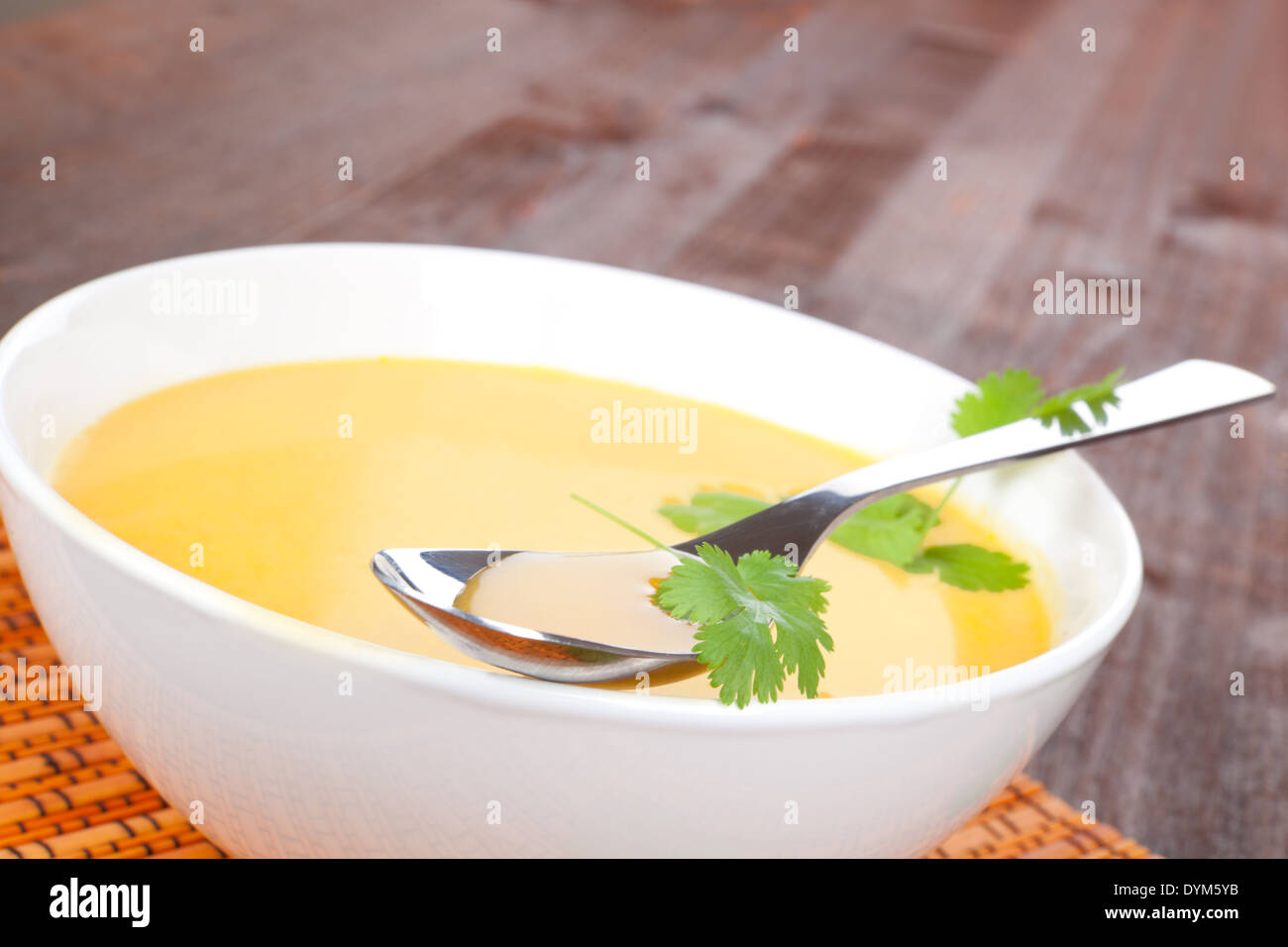 Köstliche Creme Möhrensuppe in weiße Schüssel auf dunklem Holz. Stockfoto