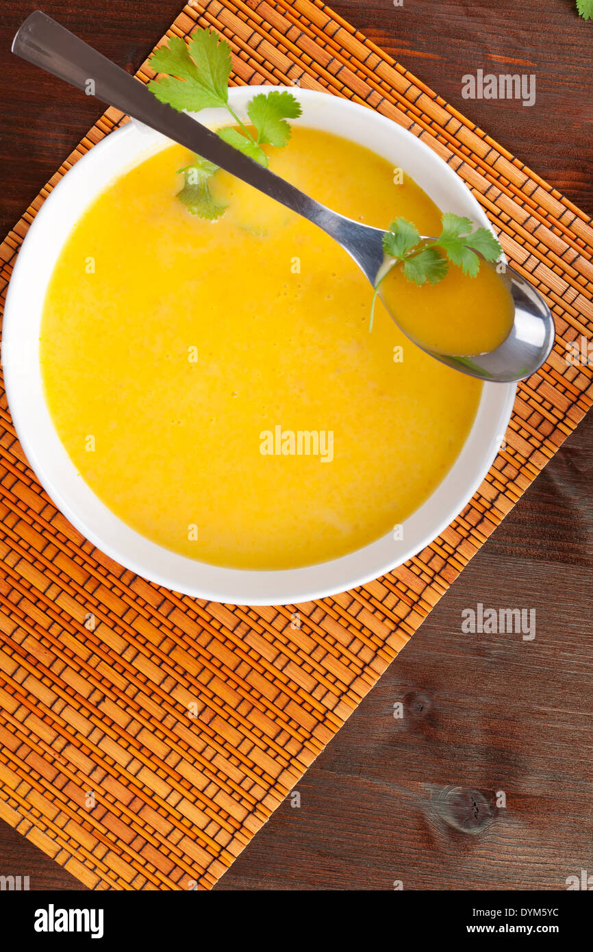 Köstliche Creme Möhrensuppe in weiße Schüssel mit Löffel auf Holztisch. Kulinarischen Suppe. Stockfoto