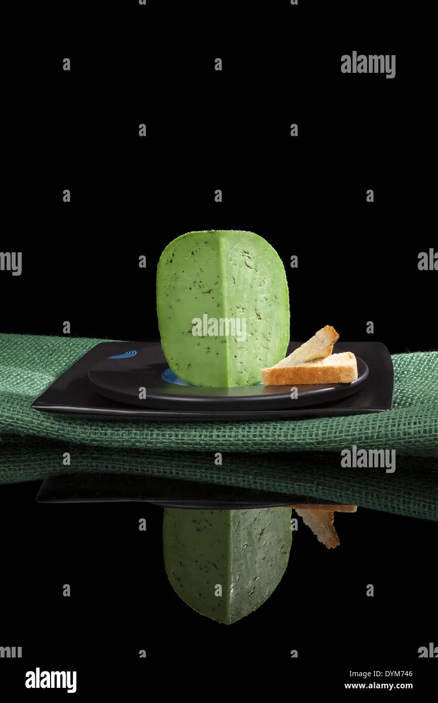 Grüne Gouda auf schwarzem Teller mit Toast auf schwarzem Hintergrund isoliert. Luxuriöse Käse essen. Stockfoto