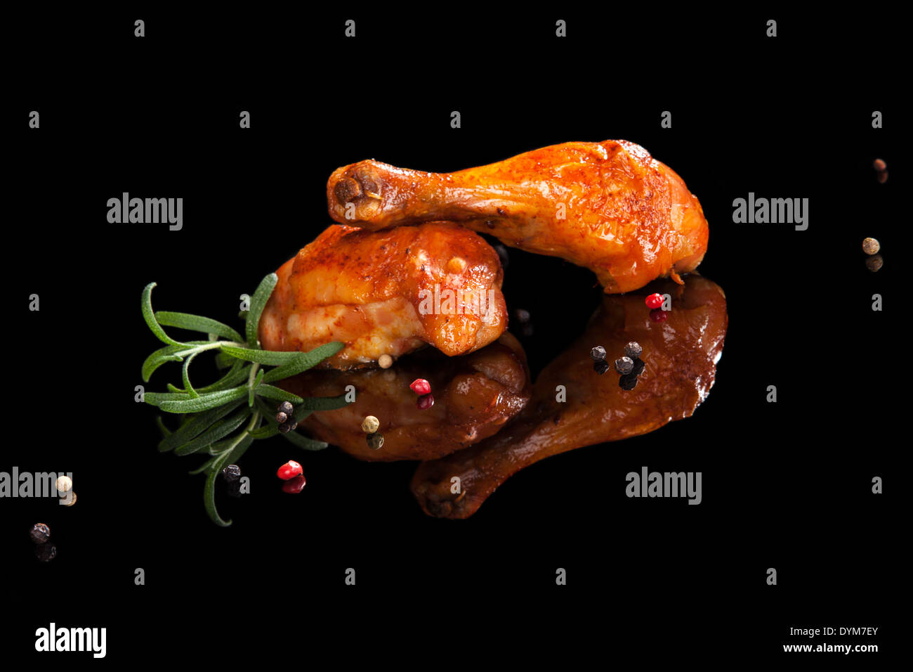 Gegrillte Hähnchen-Drumsticks mit frischen Kräutern und bunten Pfeffer auf schwarzem Hintergrund isoliert. Kulinarischen Fleisch zu essen. Stockfoto