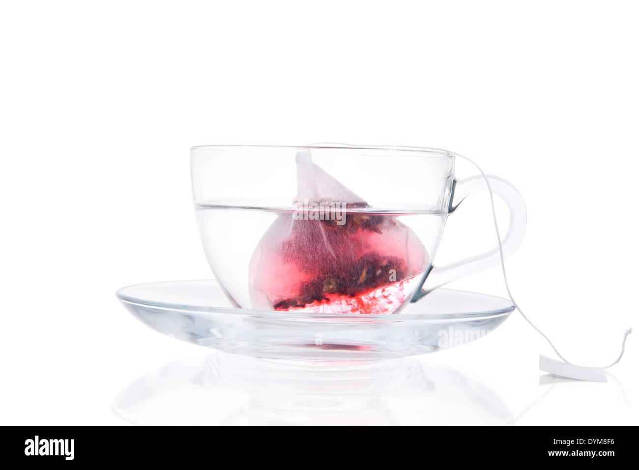 Teebeutel In transparente Becher mit Wasser, Isolated On White Background. Rote Früchtetee langsam in heißem Wasser auflösen. Gesundes Getränk Stockfoto