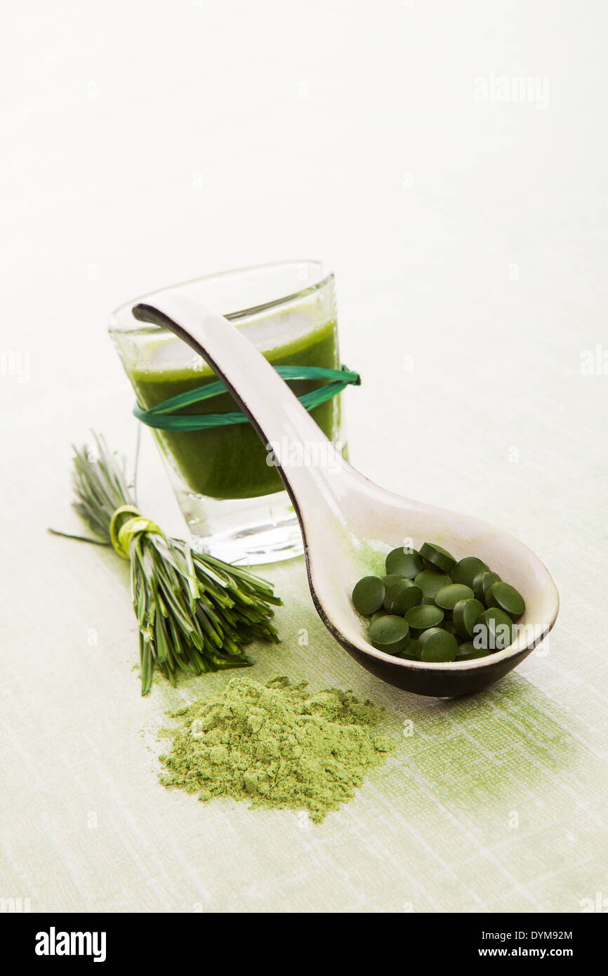 Weizengras, Gerstengras, Chlorella, Spirulina. Pflanzliche, natürliche Nahrungsergänzungsmittel. Gemahlenem Pulver, Pillen auf Löffel und grünen Saft. Stockfoto
