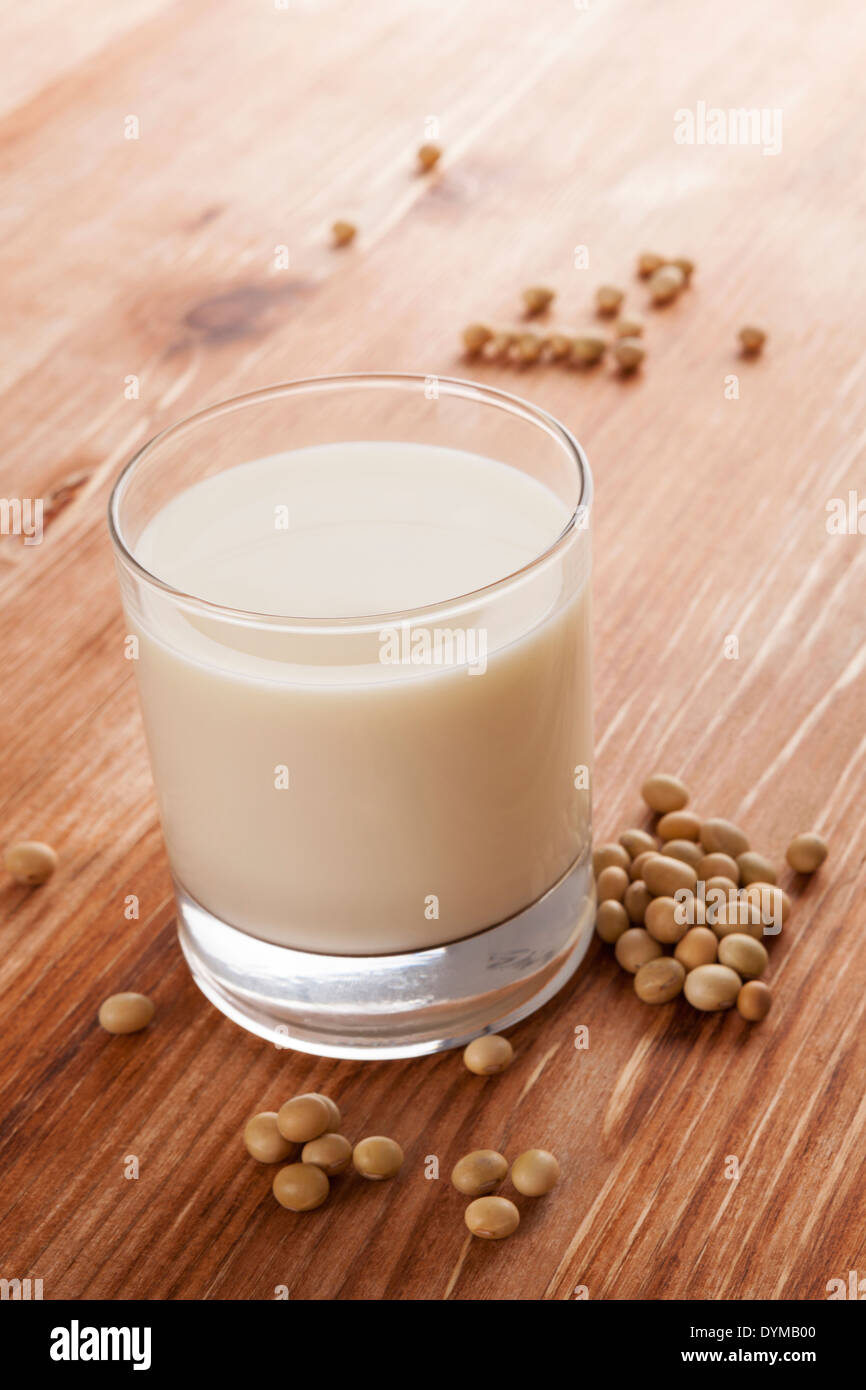 Soja-Milch im Glas und Soja-Ernte auf hölzernen Hintergrund. Vegetarische und vegane Ernährung Konzept. Stockfoto
