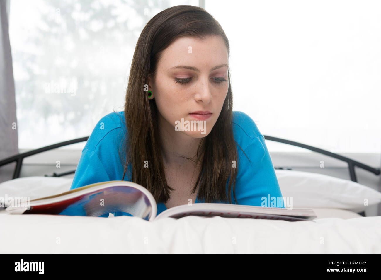 Teenager-Mädchen lesen Magazin auf Bett Stockfoto