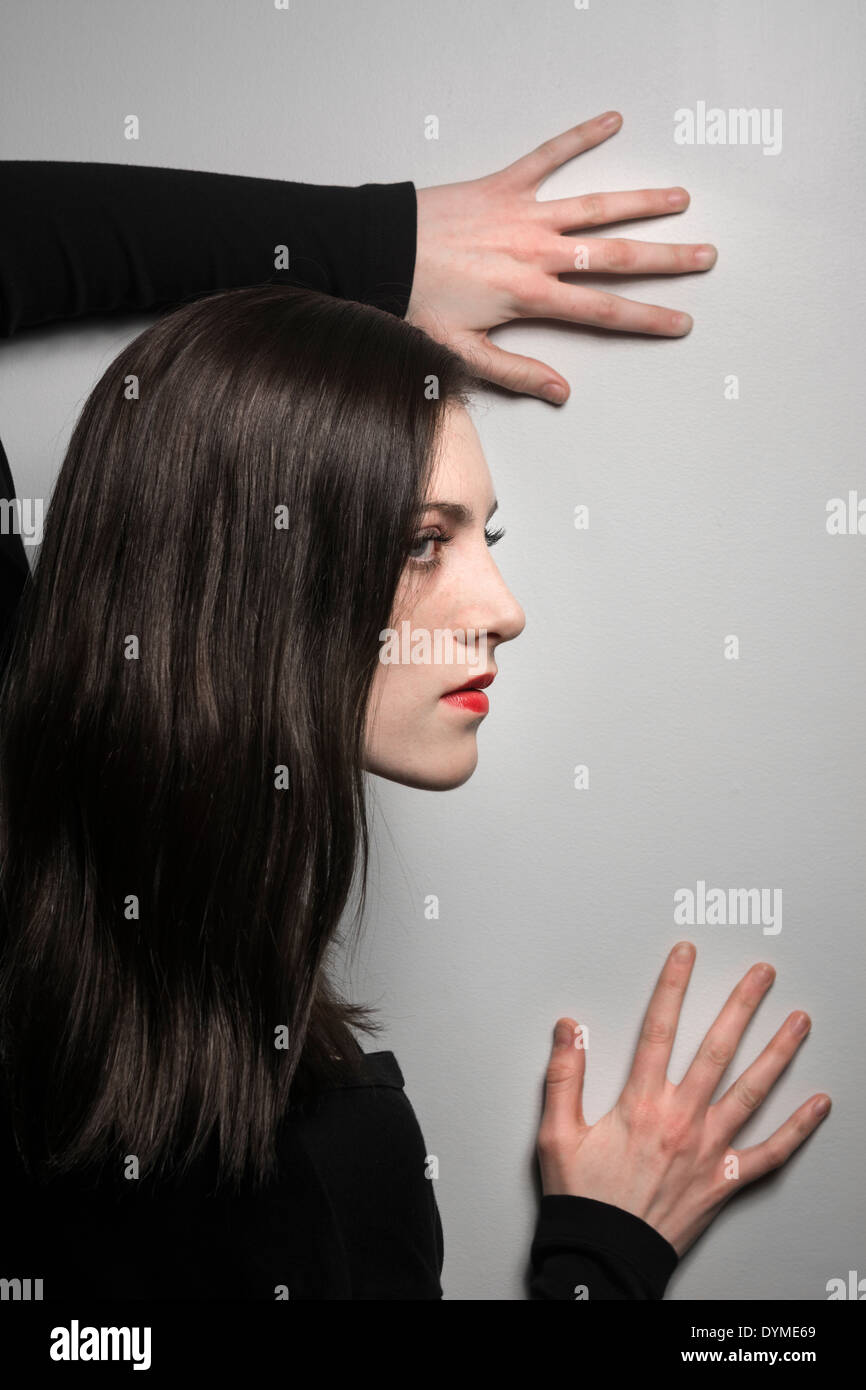 Junge weibliche Modell mit den Händen auf Wand und roten Lippenstift Stockfoto