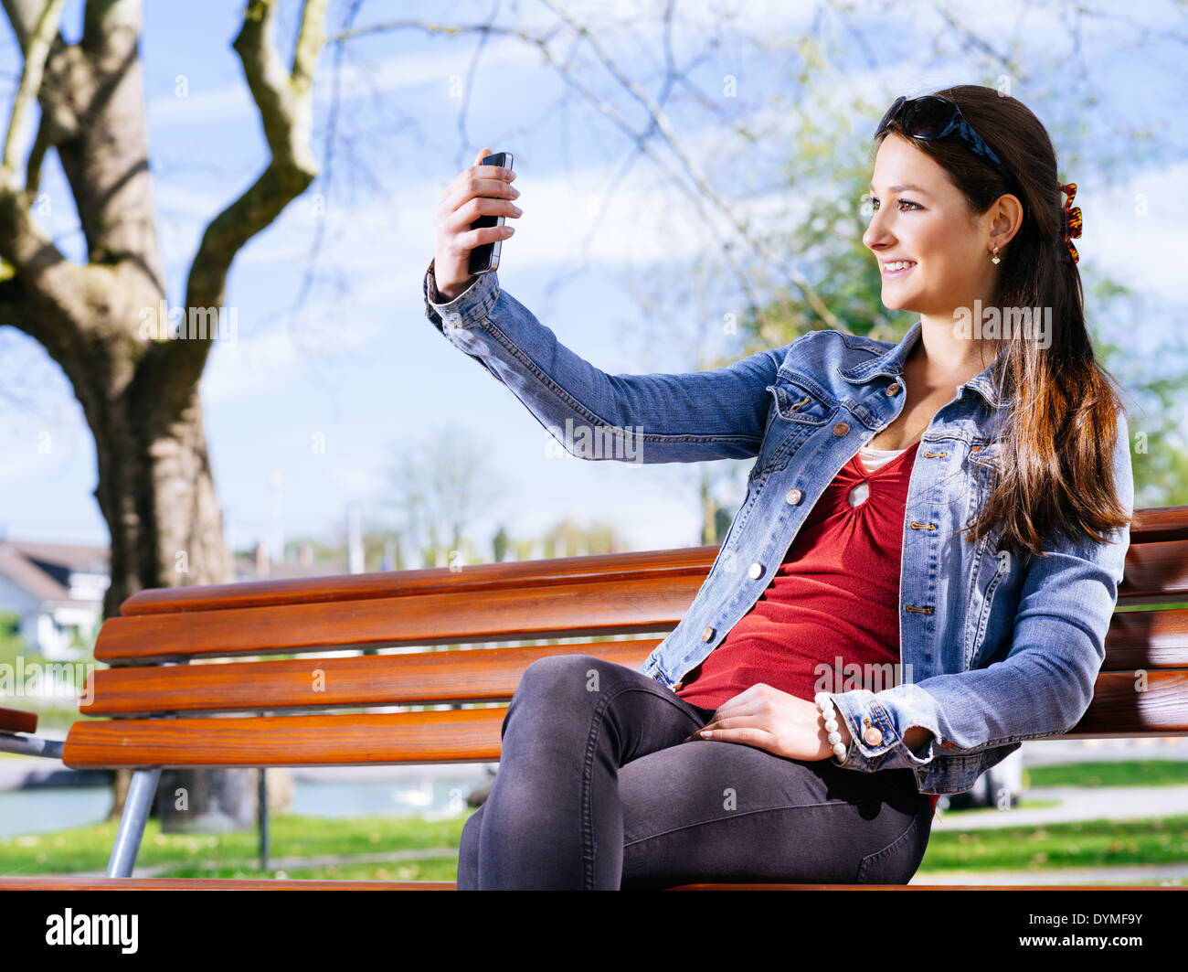 Foto von einer schönen jungen Frau, die mit einem Smartphone, um ein Selbstporträt zu nehmen. Stockfoto