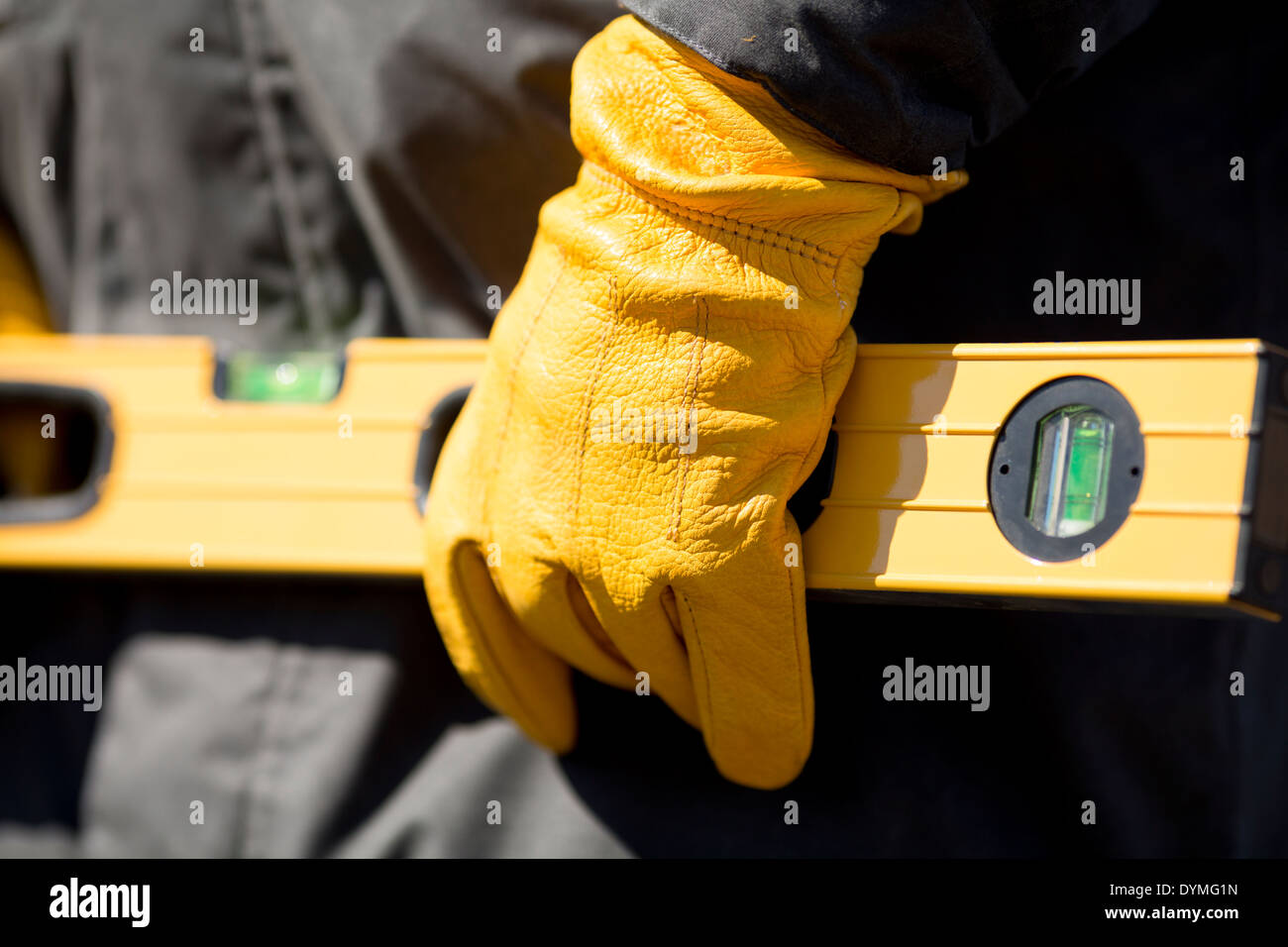 Hand des Arbeiters mit gelben Handschuh und Ebene Stockfoto