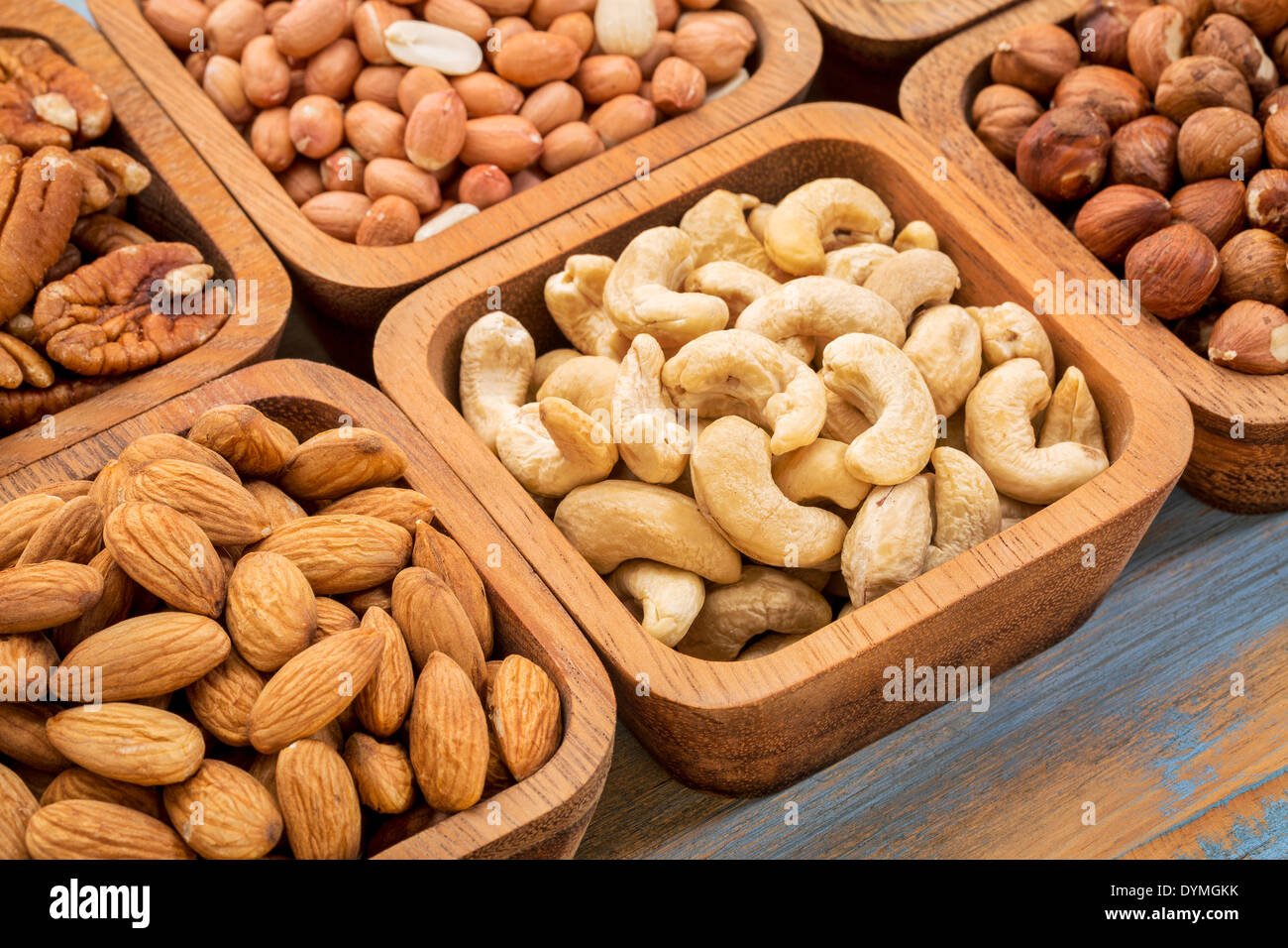 Muttern abstrakt - Pekannuss, Haselnuss, Cashew, spanische Erdnuss in Holzschalen Stockfoto