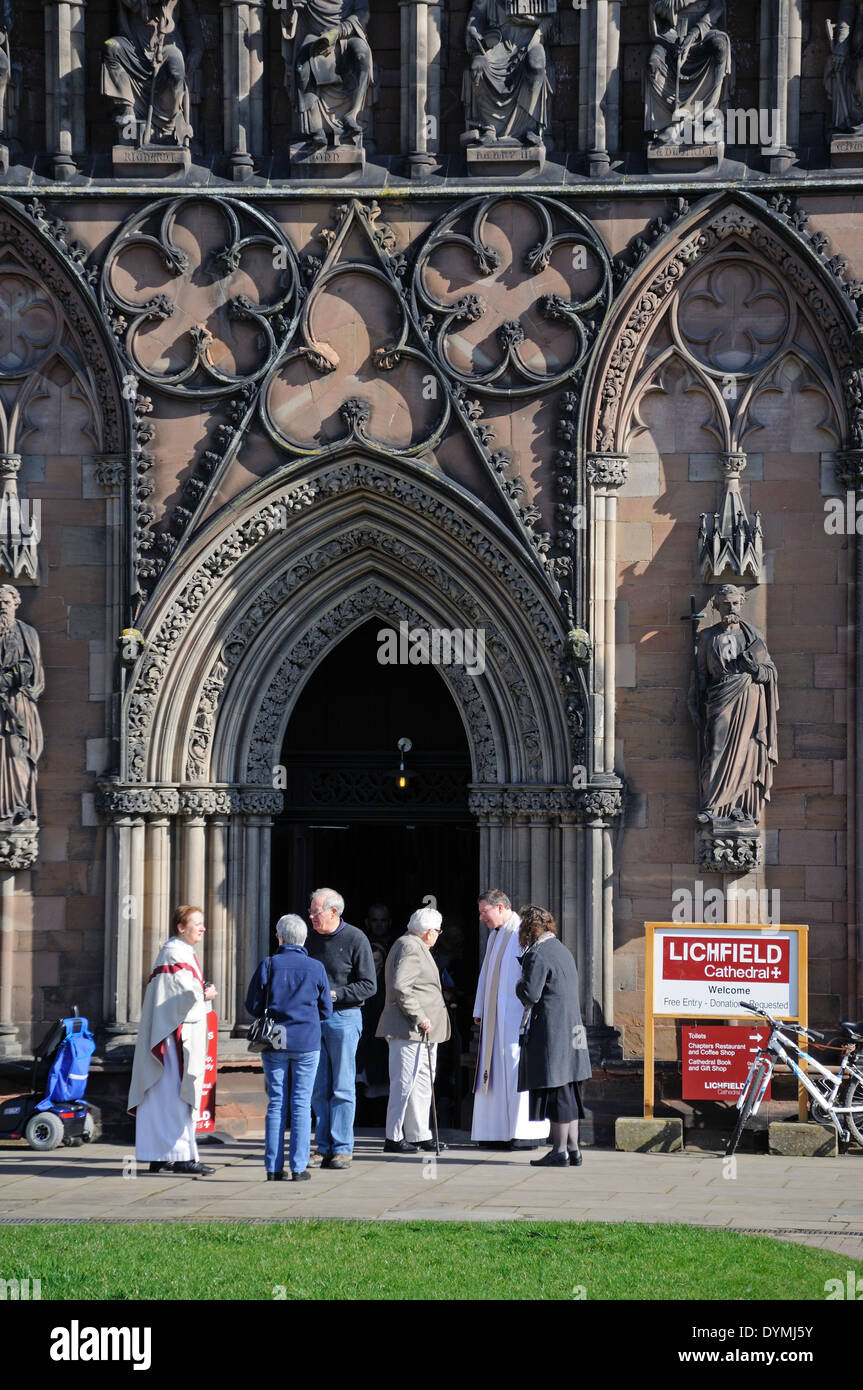 Geistliche Gruß Mitglieder der Gemeinde vor der Kathedrale Westfront Tür, Lichfield, Stäbe, England, UK. Stockfoto