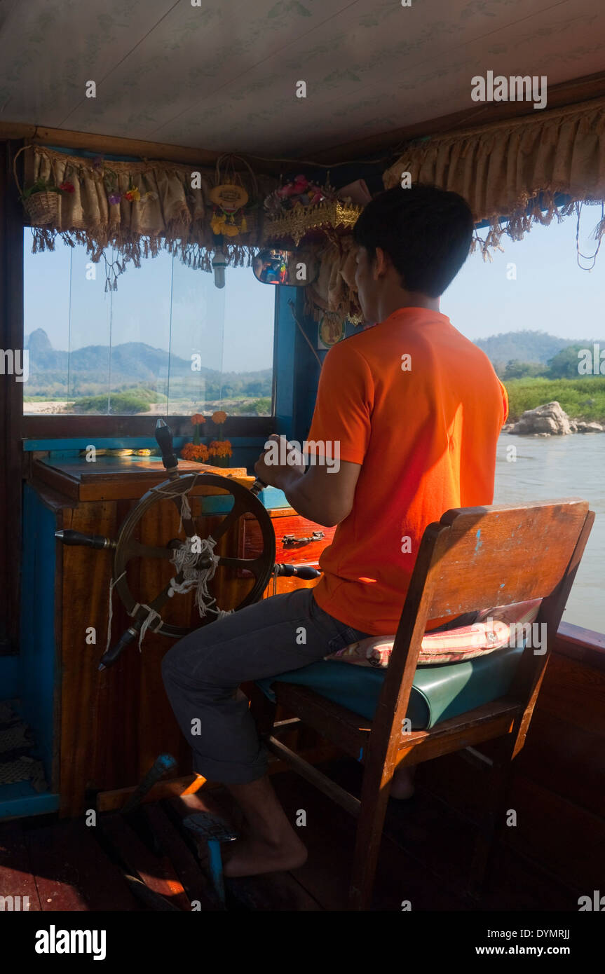 Vertikale Porträt eines laotischen Mannes als Kapitän einer langsamen Boot auf dem Mekong Fluss an einem sonnigen Tag. Stockfoto