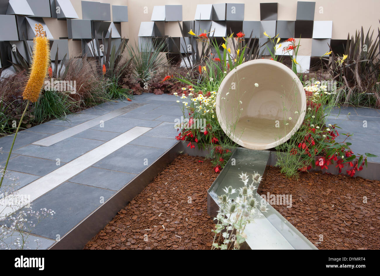 Moderner, zeitgenössischer Garten mit Gartenrill-Wasserspiel und moderner Gartenwandzaun mit Schirmwand aus Stahl, Kiesgürtel, UK Stockfoto