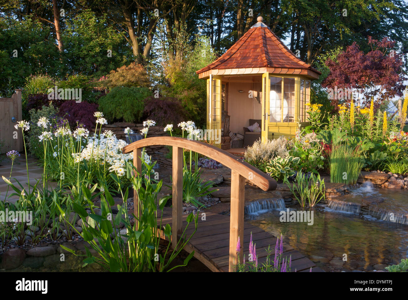 Ein Garten auf dem Land im Sommer mit einer Brücke über das Sommerhaus