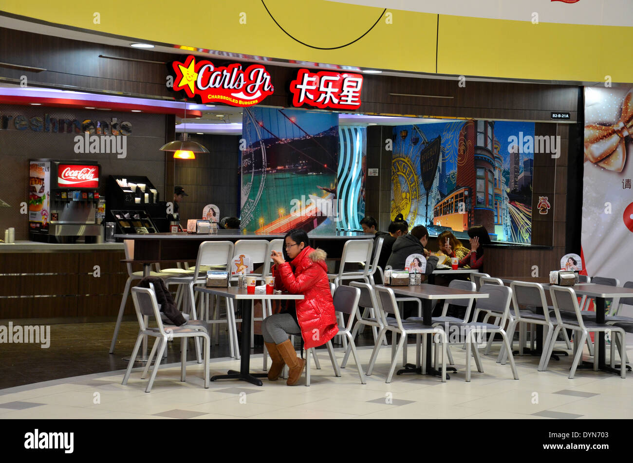 Chinesische Mädchen isst im Fast-Food Carl Jr Restaurant in Shanghai Mall China Stockfoto