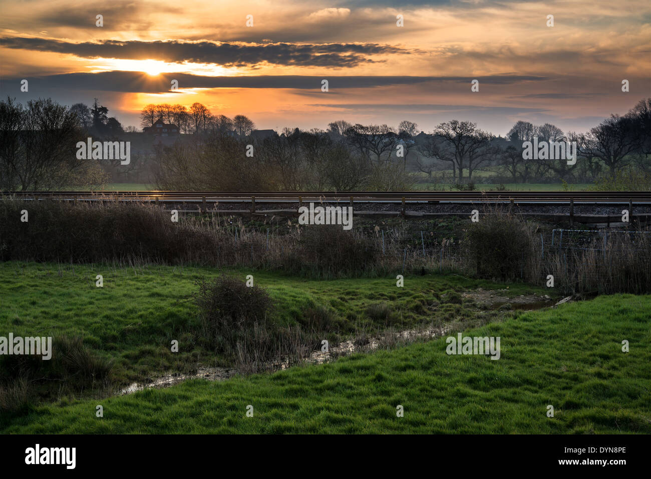 Sonnenaufgang über Bahngleise durch Landschaft Stockfoto