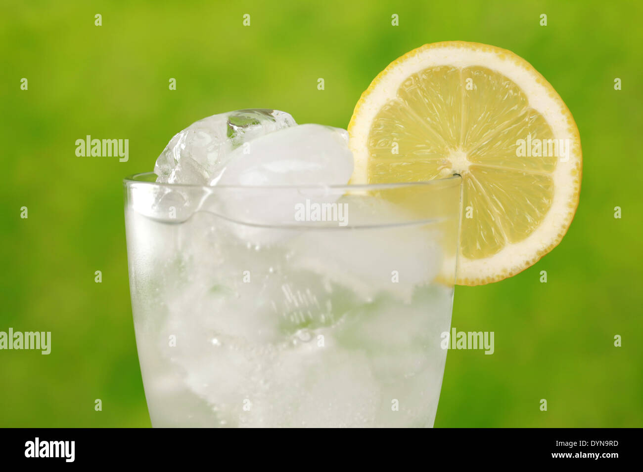 Kaltes Wasser in ein Glas mit Eiswürfeln, mit einer Zitronenscheibe serviert Stockfoto