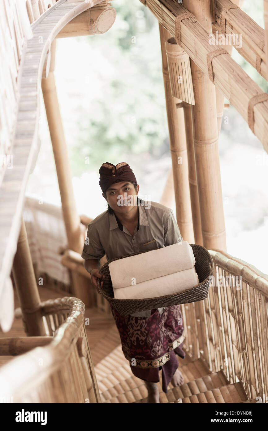 Balinesische Mann trägt gerollt Handtücher im Hotel, Ubud, Bali, Indonesien Stockfoto