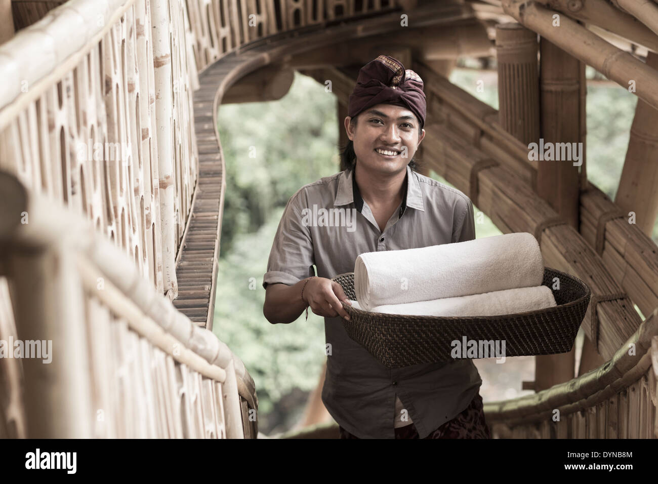 Balinesische Mann trägt gerollt Handtücher im Hotel, Ubud, Bali, Indonesien Stockfoto