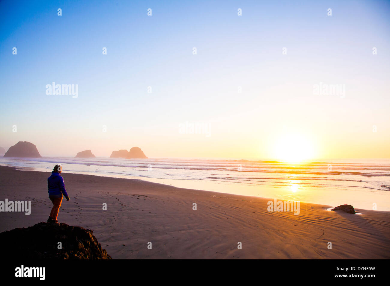 Kaukasische Frau mit Blick auf Sonnenaufgang am Strand Stockfoto