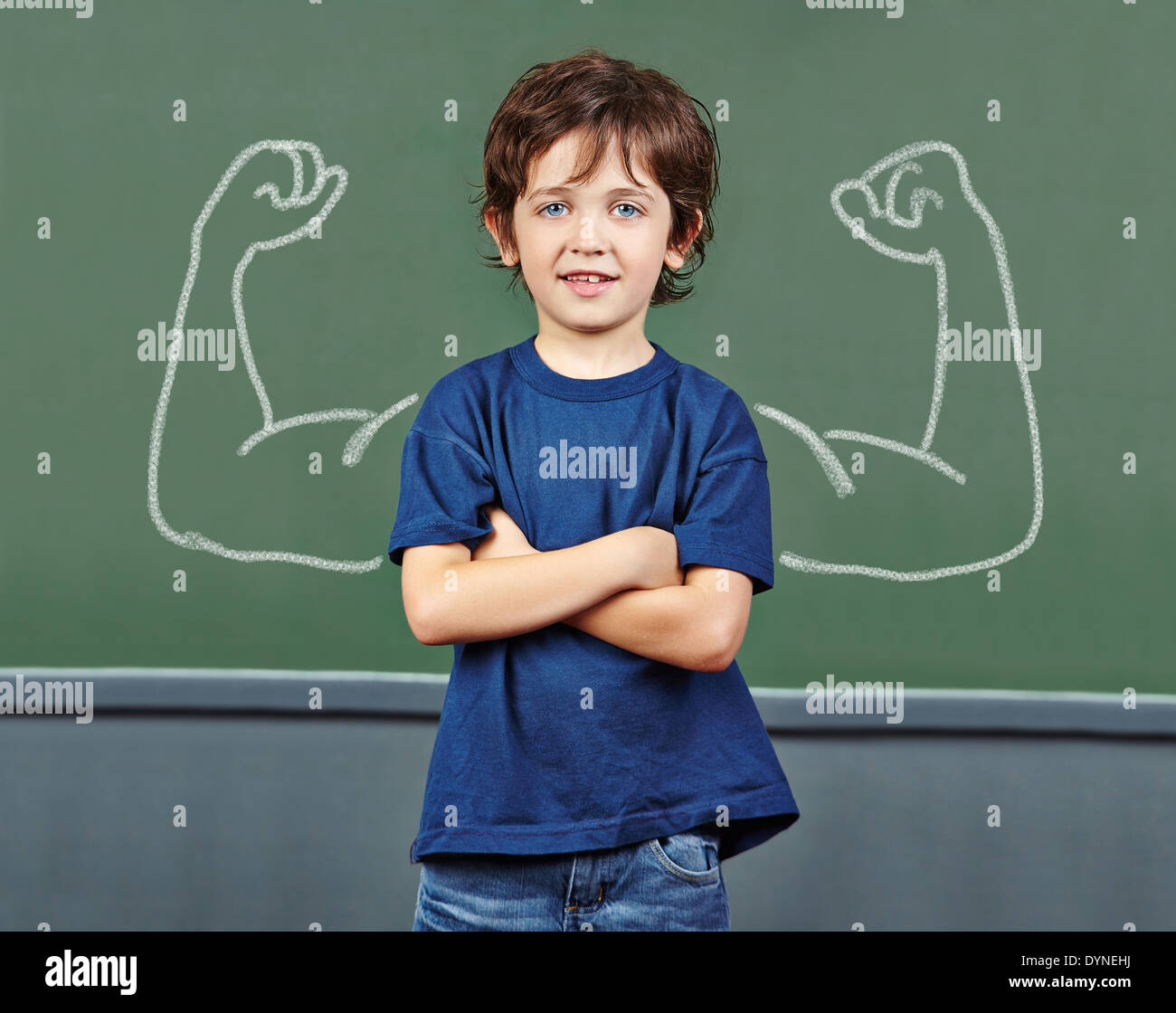 Starkes Kind mit Muskeln über die Tafel in der Grundschule Stockfoto
