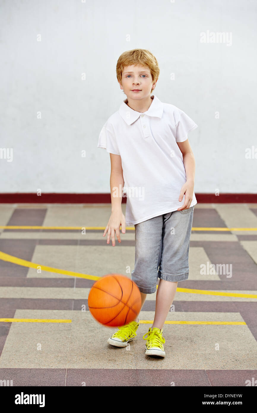 Jungen spielen Basketball auf einem Schulhof einer Grundschule Stockfoto